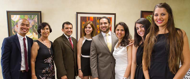 A group of business people standing in a row and smiling while looking at the camera.