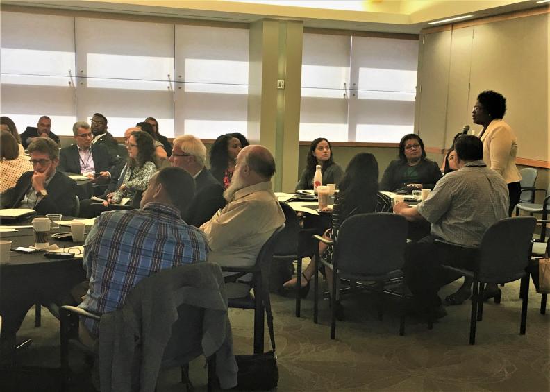 Groups of people sitting at tables listening to a woman speak on a microphone at at the LA Regional Meeting.