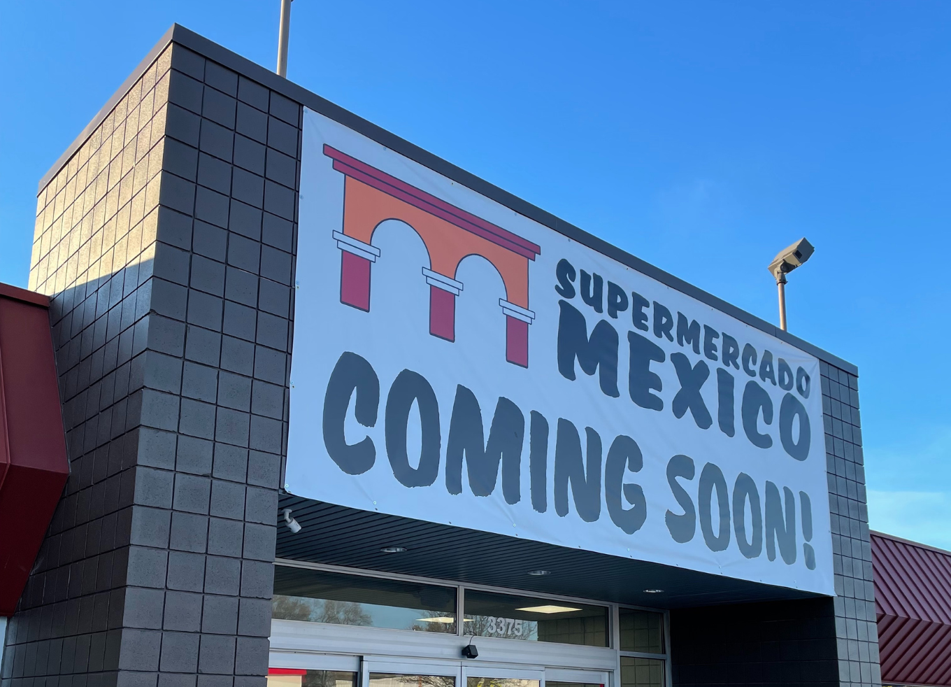 A giant banner on a building with the text "Supermercado Mexico Coming Soon"