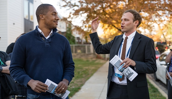 Two men talking on sidewalk